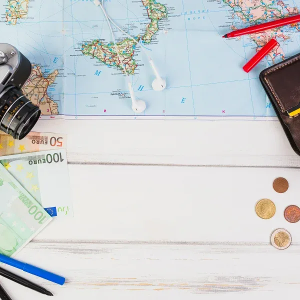A map, camera, and travel essentials arranged on a table, symbolizing travel planning and financing.
