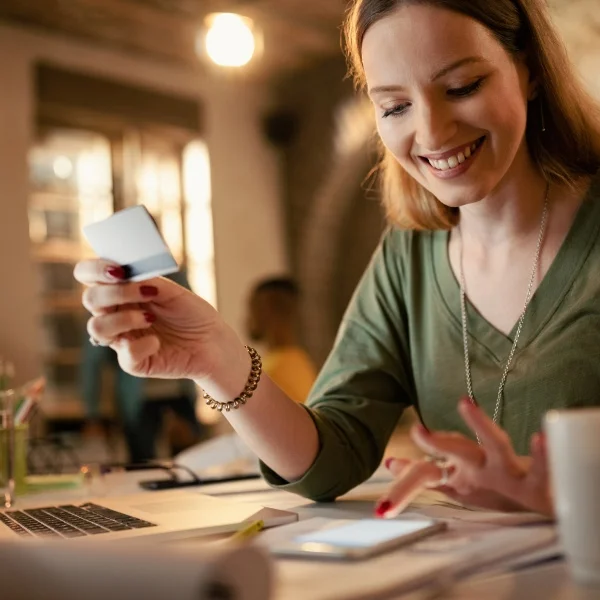 A smiling woman holding a credit card, expressing satisfaction and confidence.