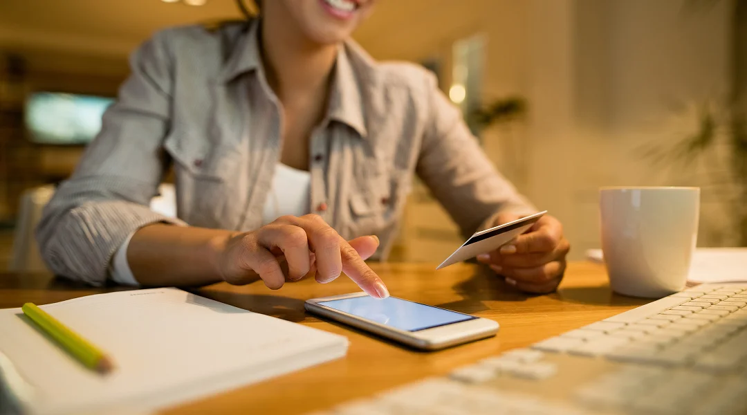 Une femme assise à un bureau utilise son téléphone.