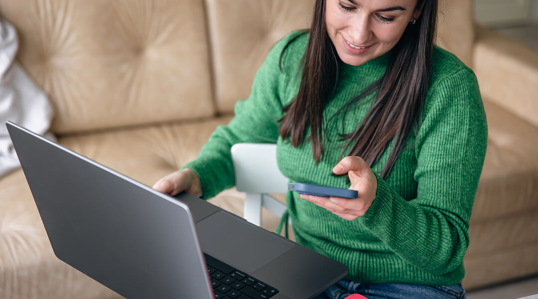 Femme utilisant son téléphone et ordinateur pour obtenir un mini prêt avec virement immédiat