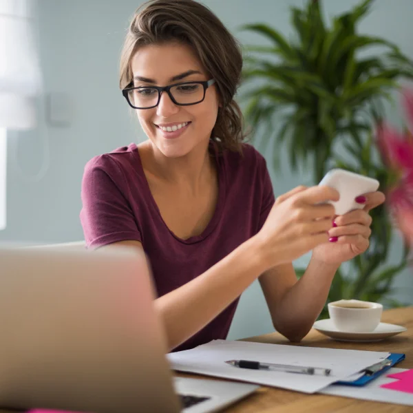 Une femme portant des lunettes utilise son téléphone, avec une mention de prêt rapide de 1500 $.