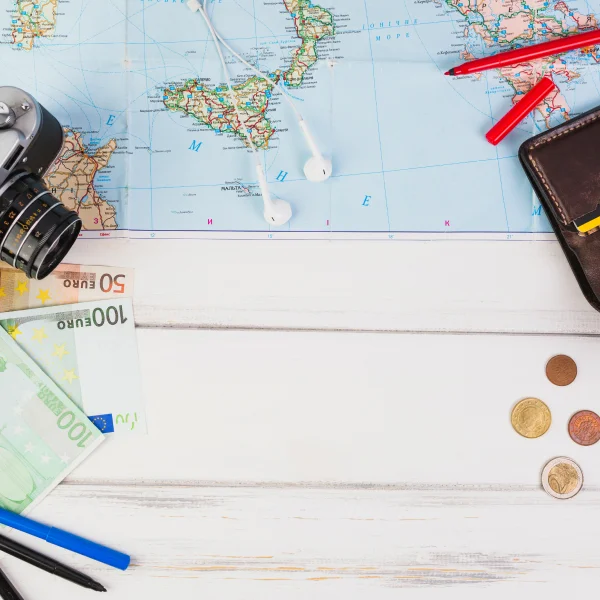 A map, camera, and travel essentials arranged on a table, symbolizing travel planning and financing.