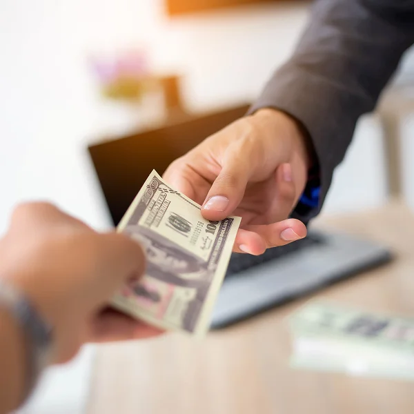 A man hands $500 in cash to another person, symbolizing a loan transaction.